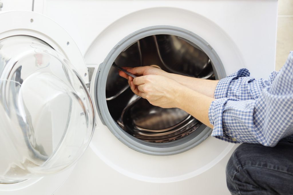 A man in a blue shirt repairing a washing machine