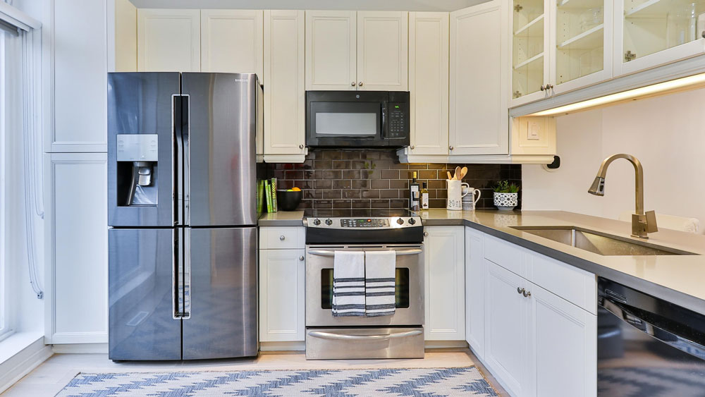 A home kitchen with a refrigerator, microwave, oven, dishwasher and sink.