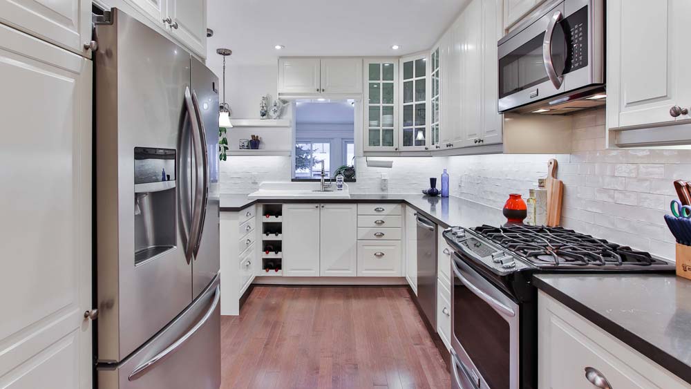 A kitchen with white cabinets and all new appliances